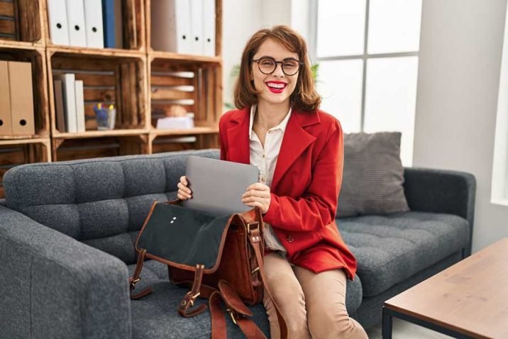 Young caucasian woman psychologist holding laptop of briefcase at psychology center